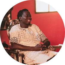 Smiling man seated in white African traditional garment
