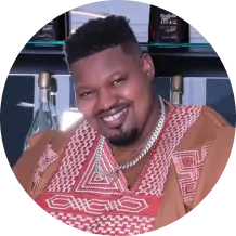 Smiling person in patterned traditional attire and necklace