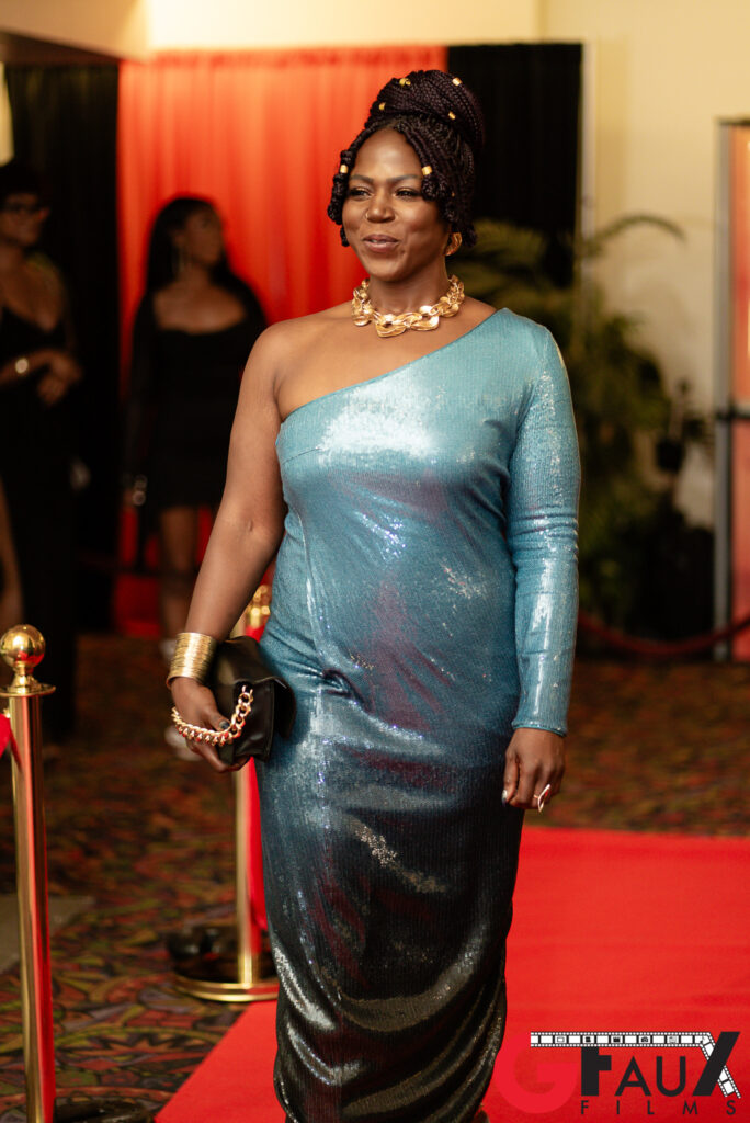 Woman in teal one-shoulder gown on red carpet