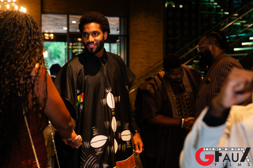 Man in patterned robe greeting guests at event