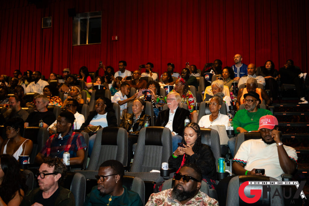 Audience seated in red-curtained movie theater
