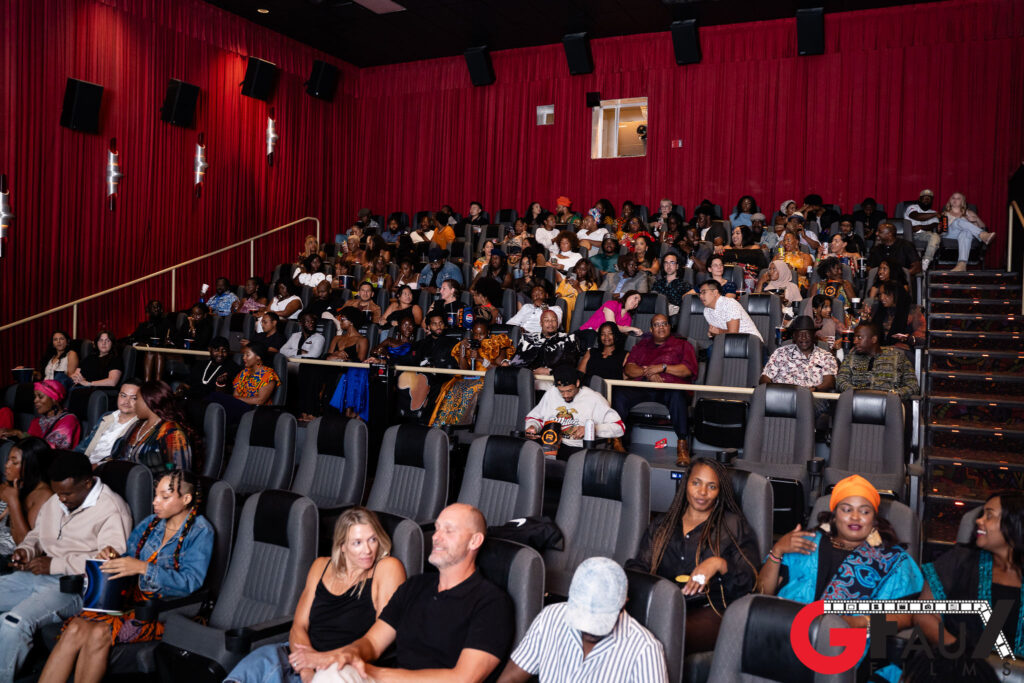 Audience seated in red-curtained movie theater