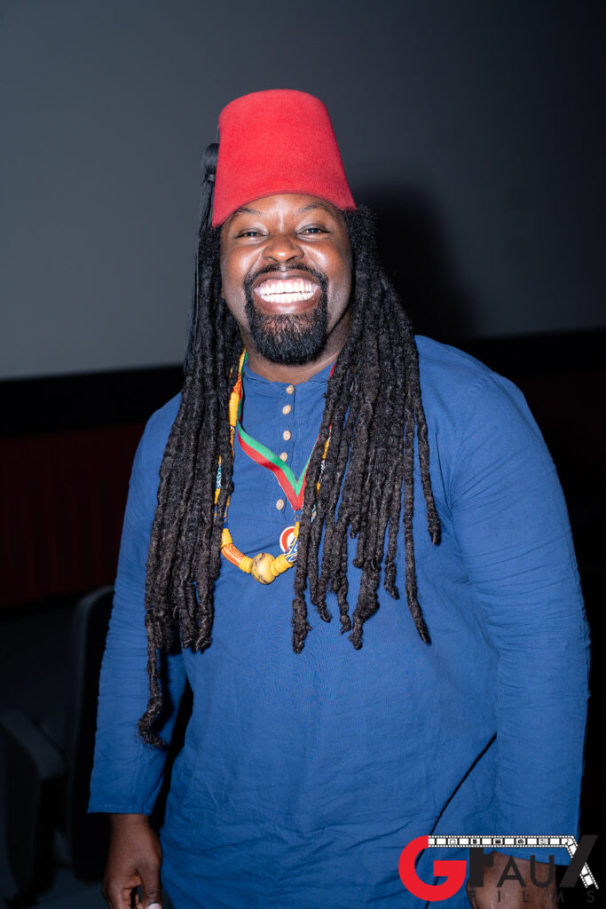 Smiling man with dreadlocks wearing red fez