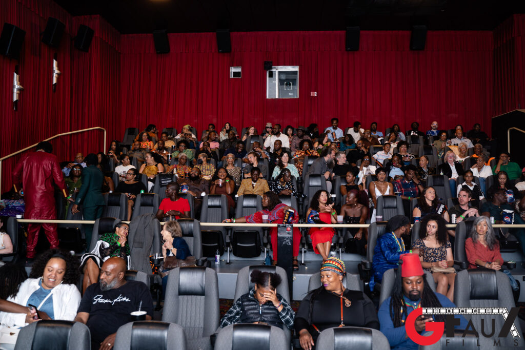 Audience seated in theater with red curtains